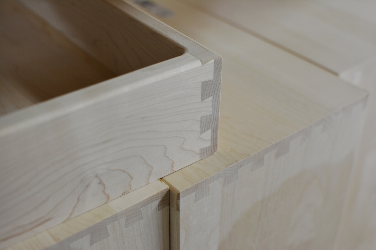 Close-up of interlocking dovetail joints at pale wood drawer corners